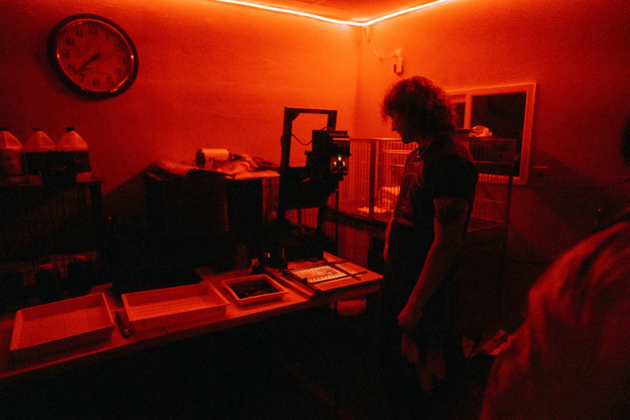 Fotograf w ciemni pod czerwonym światłem podczas obróbki zdjęcia